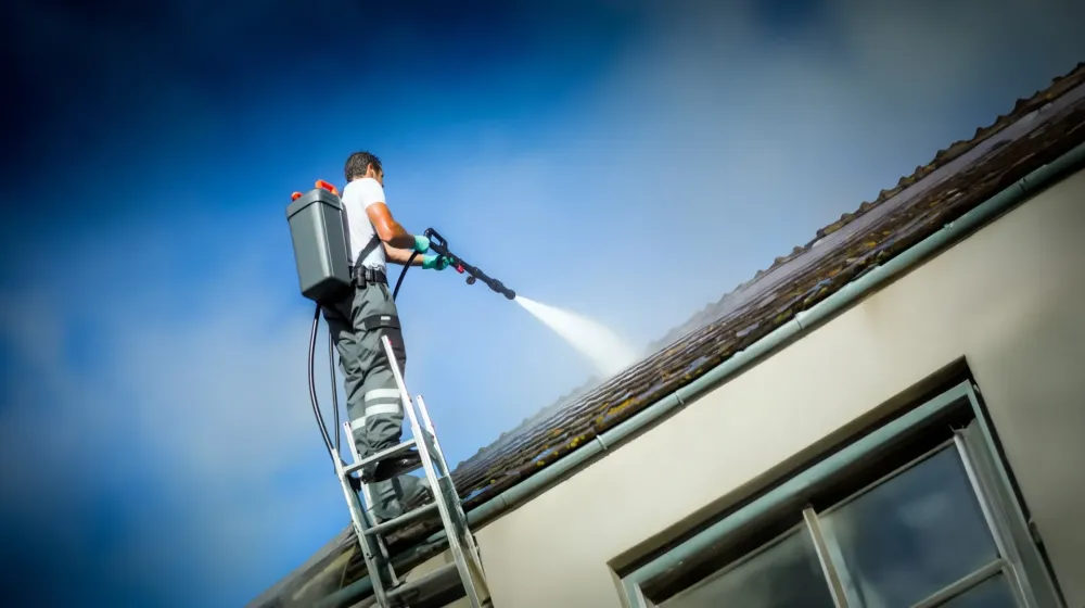 employé qui démousse un toit