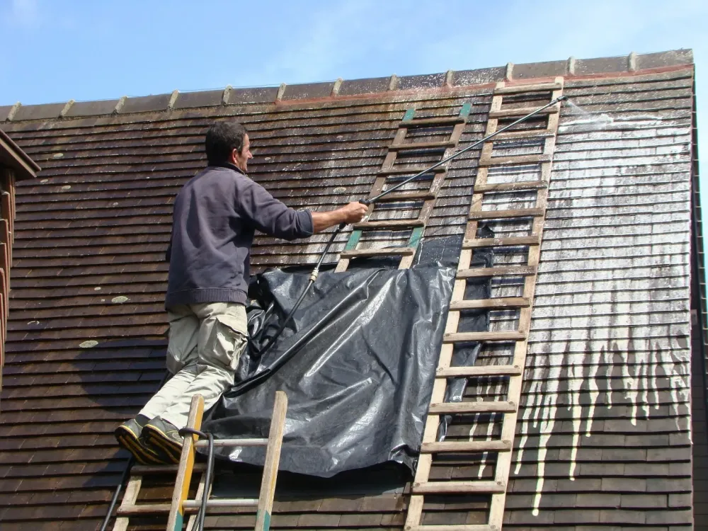 employé qui démousse un toit